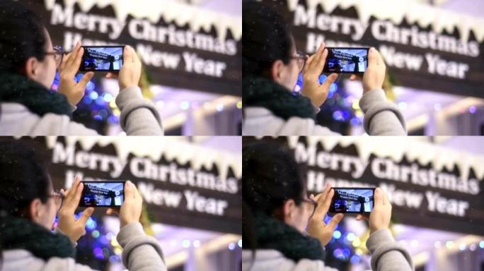 中国女孩用手机在圣诞树下拍照