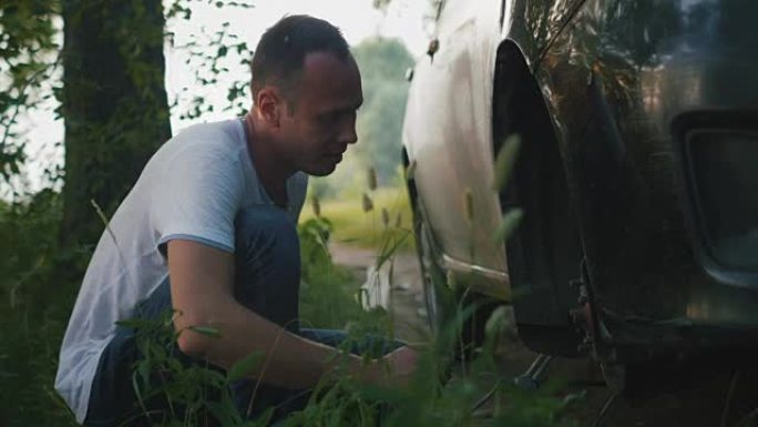 强壮的人在树林里修理汽车的车轮