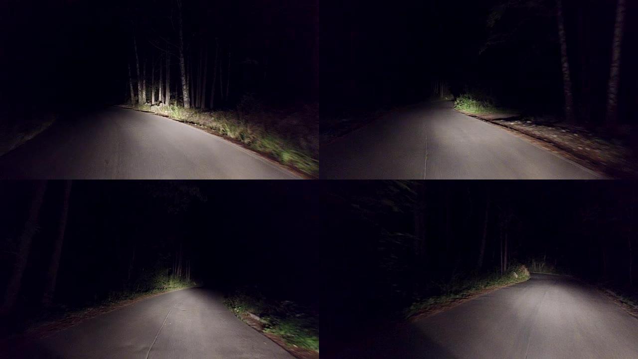 在黑暗森林的乡村道路上夜间行驶。4k