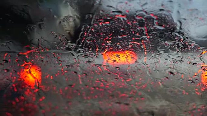道路上美丽多彩的模糊交通视频。雨水流动和雨刷在汽车前风挡玻璃上