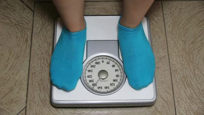 女性蓝色袜子站在体重秤上