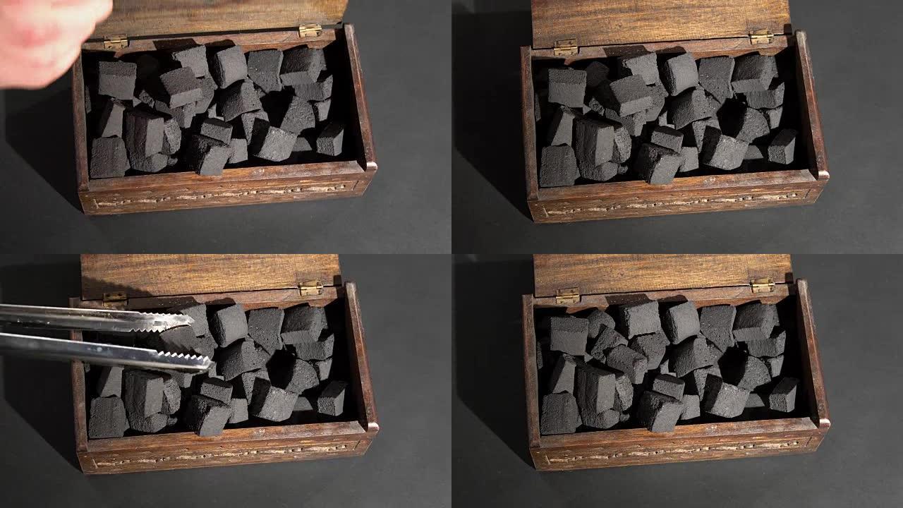 盒子里黑炭的特写。手用压煤打开盒子。
