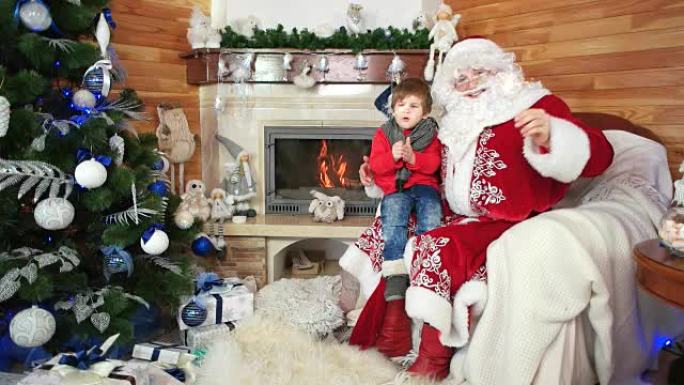 小男孩坐在圣诞老人的腿上，有烟火，节日气氛，孩子和快乐的圣诞老人