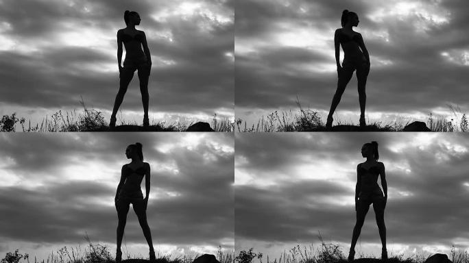 苗条的女孩照片模特在球场上多云的天空的背景下摆姿势拍照，黑白视频，女人的剪影