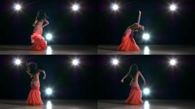 美丽苗条的女人肚皮舞跳舞，黑色，背光，慢动作