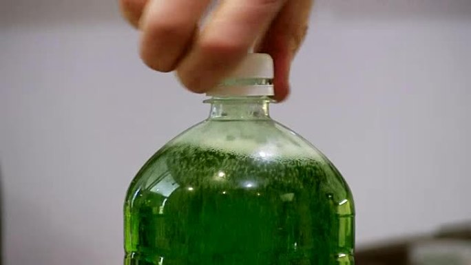 男人是失败的，打开一个塑料瓶的盖子，里面装满了苏打绿发泡慢动作