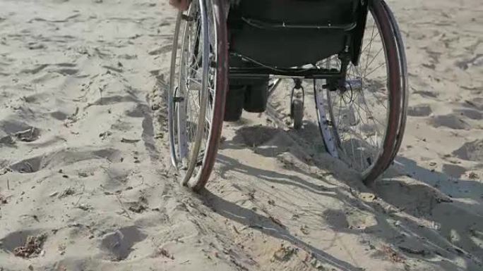 轮椅上的残疾人被困在沙中，行动困难残疾人坐在轮椅上的残疾人