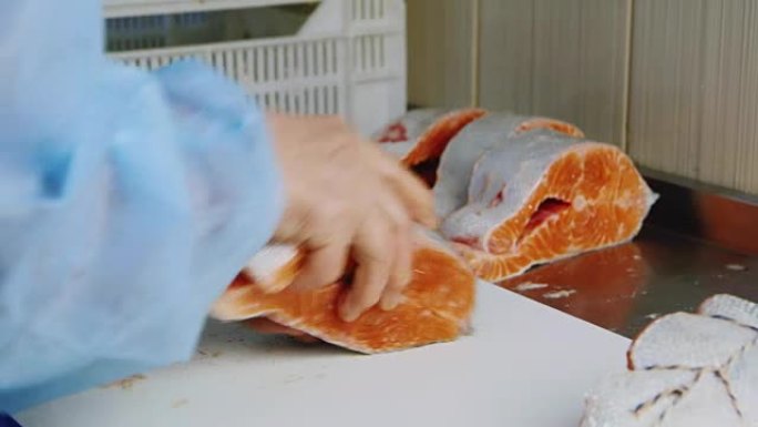 鱼厂的体力劳动。一名妇女的手正在加工用绳子包裹的红色鱼的尸体，以进一步吸烟