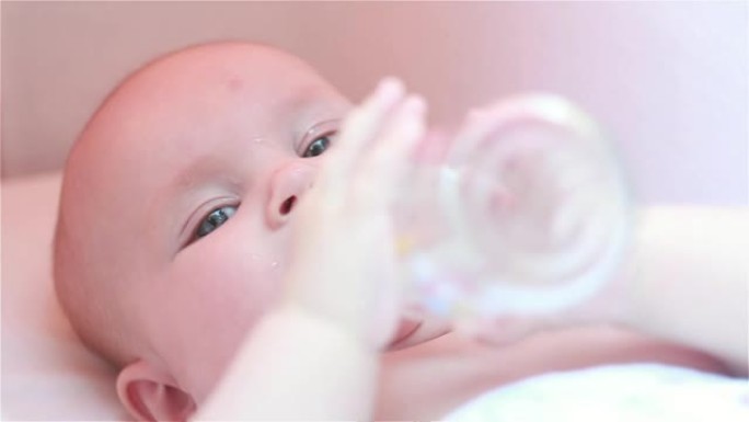 婴儿在婴儿车里，用瓶子喝水