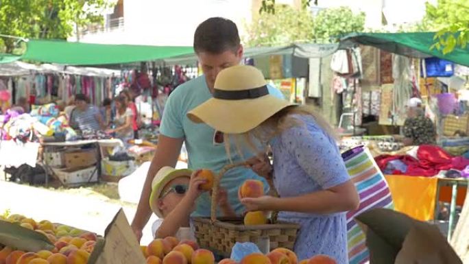 希腊塞萨洛尼基市场的年轻家庭选择桃子