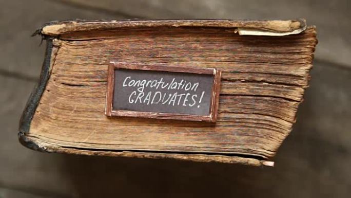 祝贺毕业生在桌上的文字和老式书籍