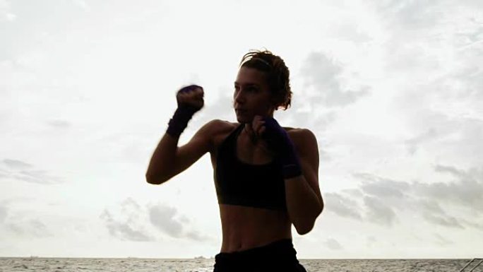 硬汉美女shadow boxing。美丽的女拳击手早上在海边的沙滩上训练，慢动作的出拳