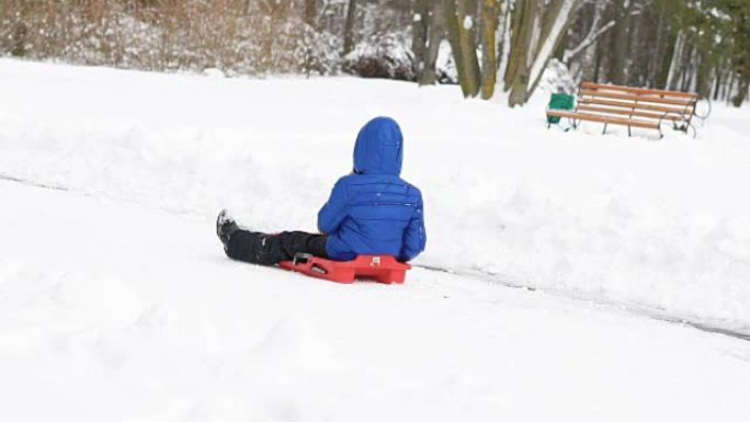 在冬季公园骑雪橇的孩子。慢慢地