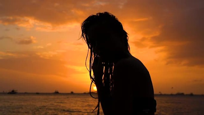 性感的湿头发女孩，穿着比基尼在日落海滩摆姿势