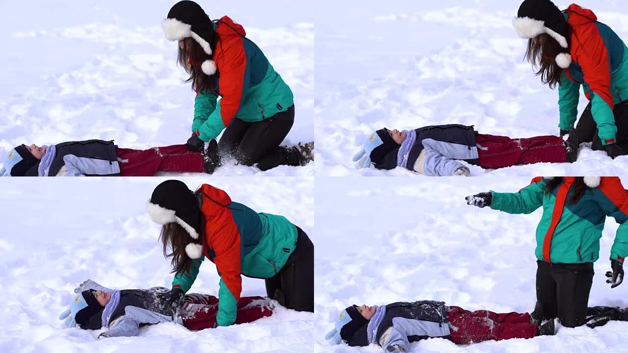 妈妈和小儿子在雪地里玩得很开心。他们笑着掉进雪地里。