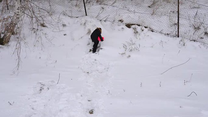 十几岁的男孩试图骑在山坡上。公园里孩子们的冬季乐趣。阴天的冬日。