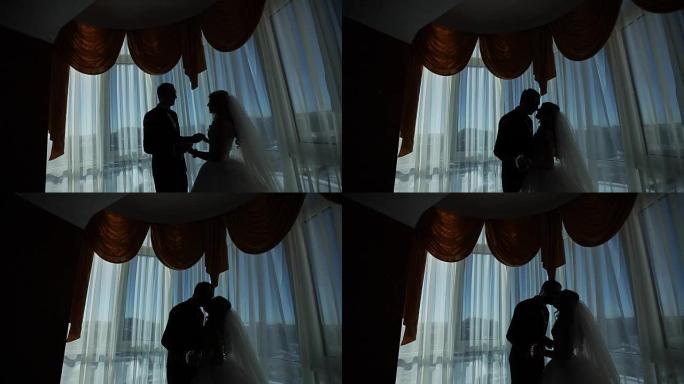 快乐的奢华新娘和新郎站在富裕房间的窗灯前