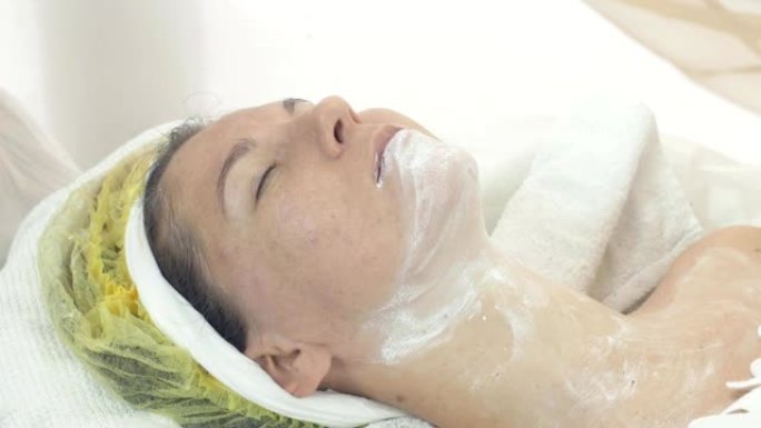 美容师在美容院用餐巾纸擦掉女人的脸和脖子