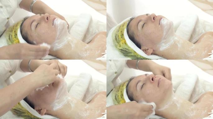 美容师在美容院用餐巾纸擦掉女人的脸和脖子