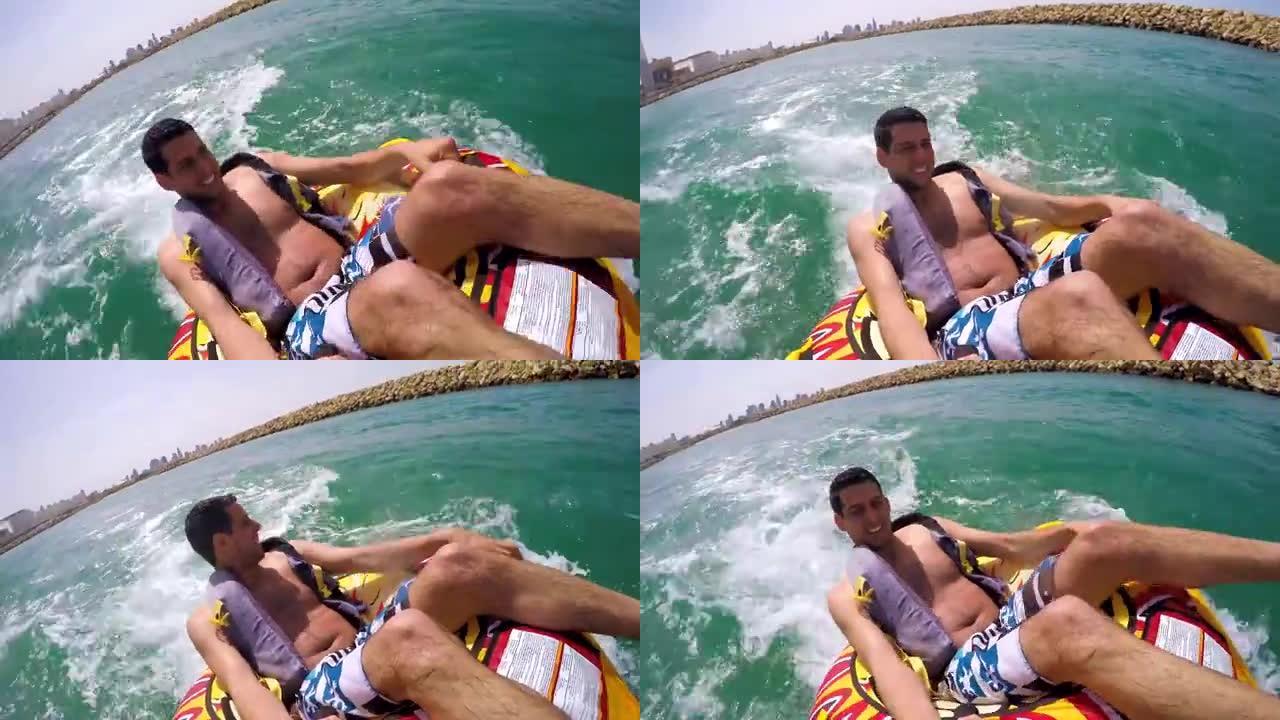 男子坐在充气环上，被一艘船拖入水中，用Go Pro相机记录自己