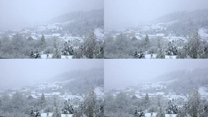 雪落在树木繁茂的山脚下的小村庄上