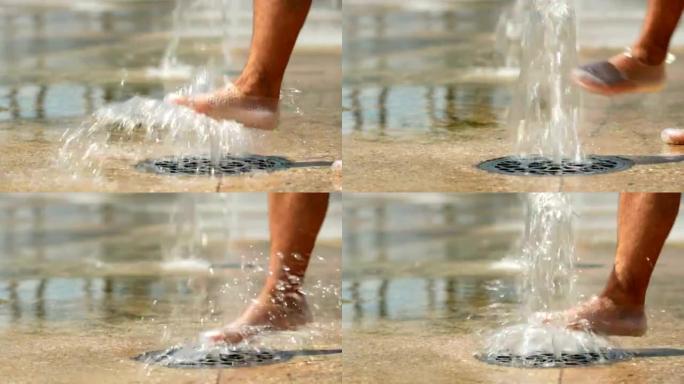 水从地下涌出。人的脚玩水。水流落在地上。特写