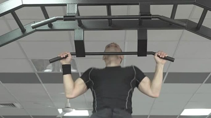 运动员肌肉健身男模在健身房的单杠上拉起