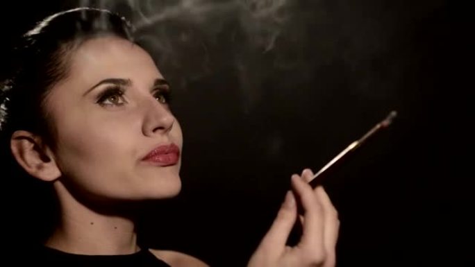 美女在黑色背景上的烟嘴里抽烟