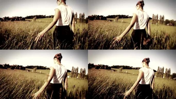 女人在田野里抚摸长草
