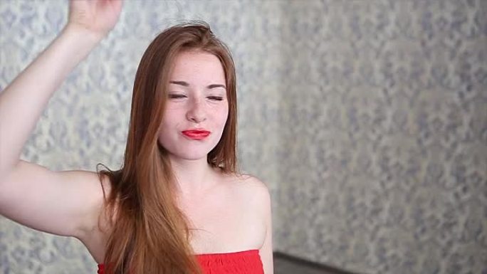 浅蓝色背景上穿着红色连衣裙的性感年轻红头发女孩