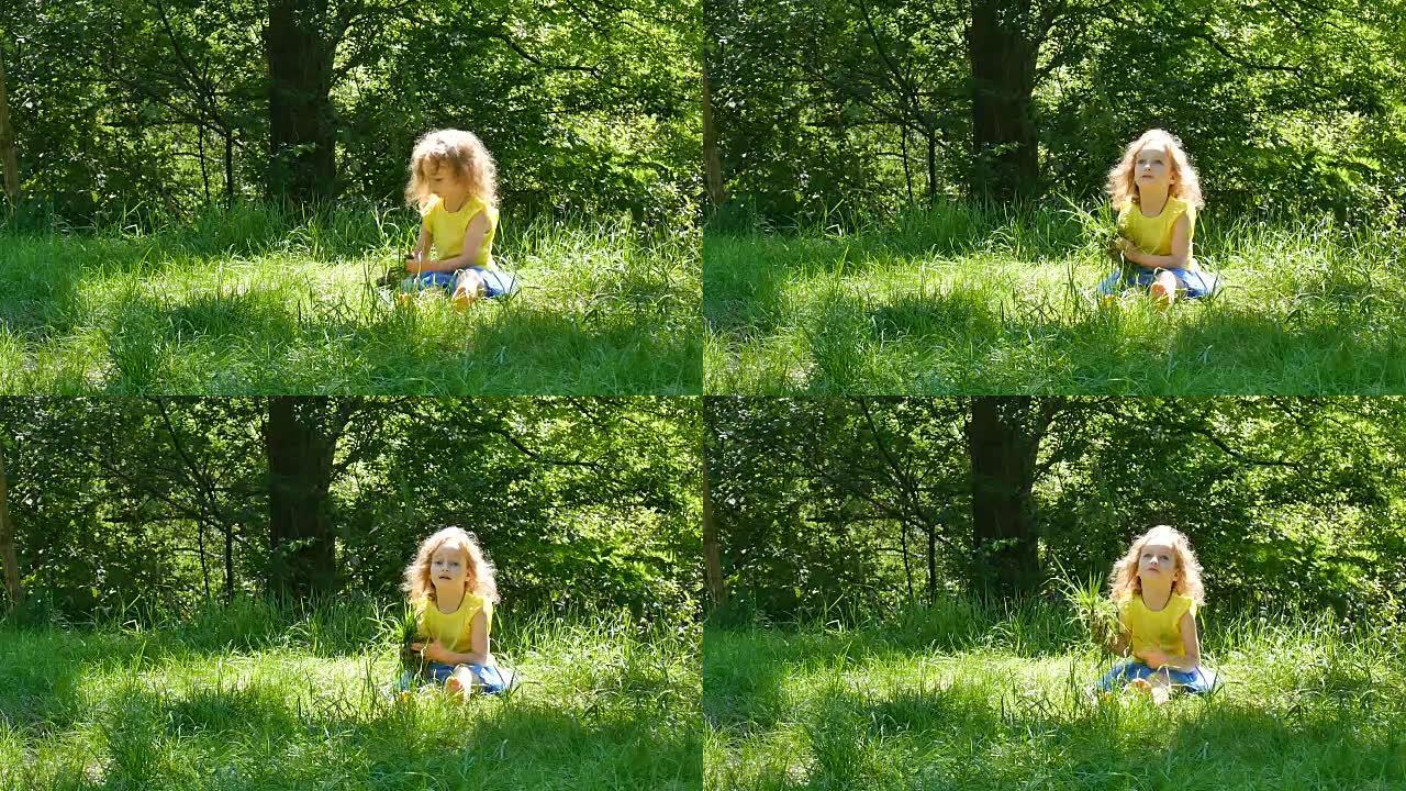 顽皮的小女孩在阳光明媚的日子里在公园里享受温暖的夏日天气。女孩子捡起绿草，看着镜头。