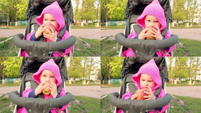 女婴坐在婴儿车里吃苹果