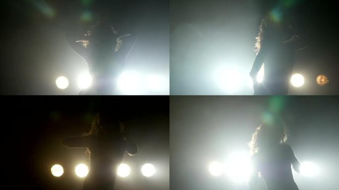 一个女孩在背景灯上跳舞的剪影。慢动作