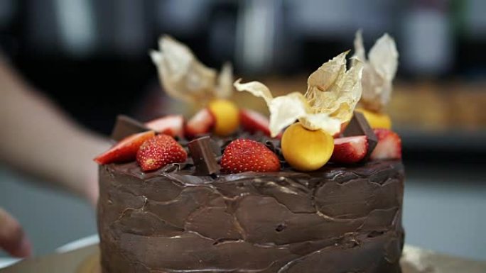 美丽的乡村黑巧克力磅蛋糕，顶部有草莓和鹅角浆果