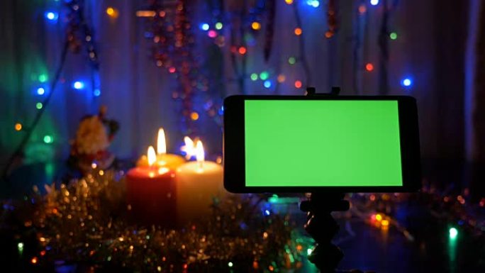 新年的背景，在前景的智能手机与绿屏。一个很好的机会来添加你的问候视频。