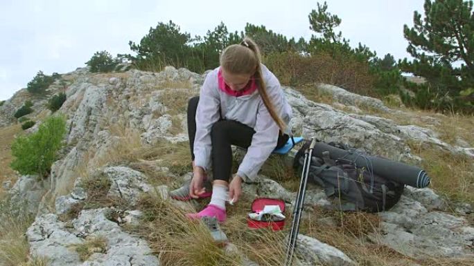 年轻的徒步旅行妇女在山上使用急救箱扭伤了脚踝