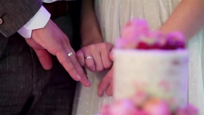 新婚夫妇展示着焦点的戒指，变成了美丽的婚礼蛋糕，装饰着天然玫瑰绽放和浆果无脸特写架焦点。宴会接待安排