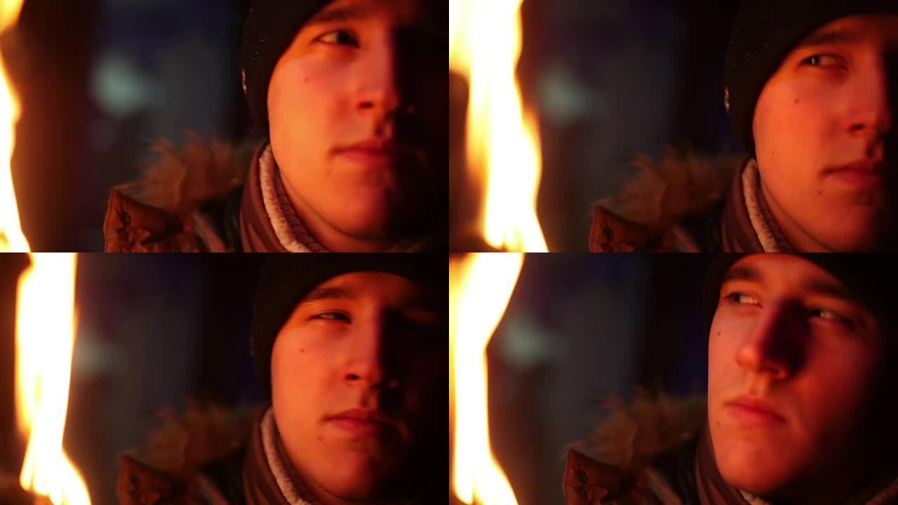 穿着冬装的年轻人在火光下看着相机