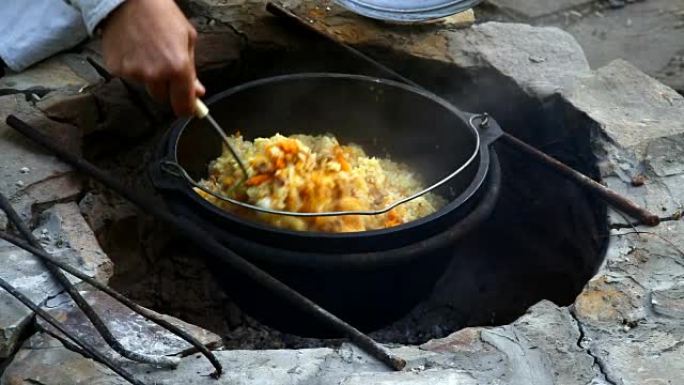 乌兹别克斯坦国家菜在大火上的大型铸铁大锅中抓饭。混合即发抓饭