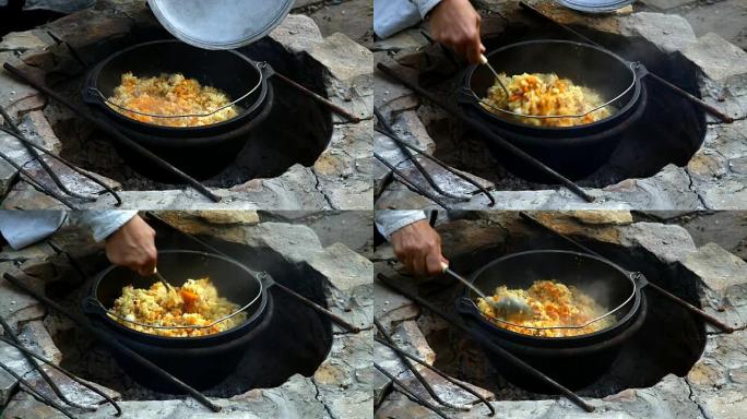 乌兹别克斯坦国家菜在大火上的大型铸铁大锅中抓饭。混合即发抓饭