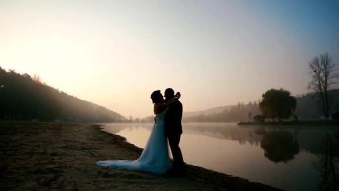 两对幸福的新婚夫妇在婚礼当天的傍晚在日落的浪漫湖上进行甜言蜜语和接吻