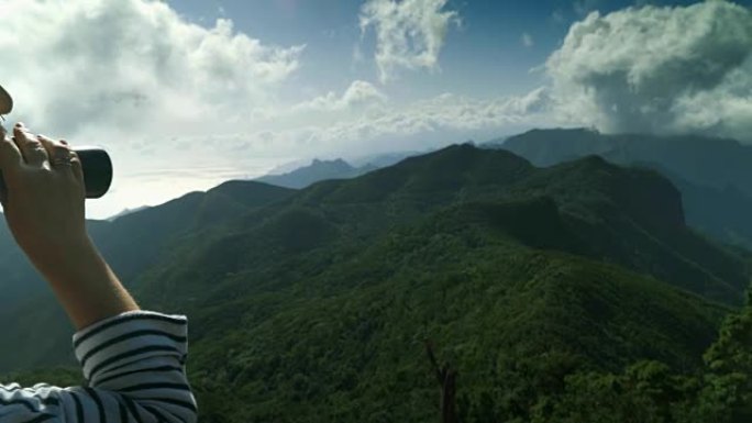 游客用双筒望远镜在海洋中的一个岛屿上的山顶火山峰火山岛