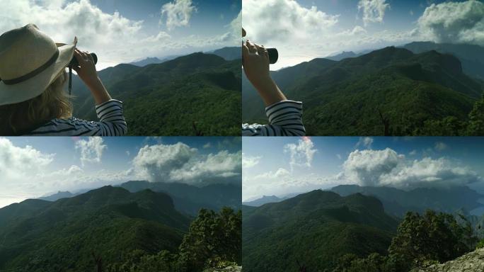 游客用双筒望远镜在海洋中的一个岛屿上的山顶火山峰火山岛