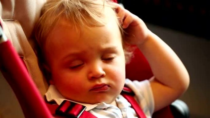 婴儿睡着了，摸摸他的头发。蹒跚学步的婴儿在椅子上睡着了