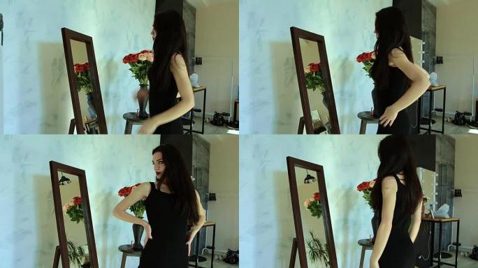 穿着黑色连衣裙的美丽性感黑发女郎在镜子前摆姿势