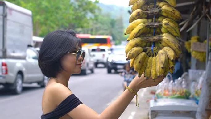 年轻的亚洲妇女在市场上购买香蕉