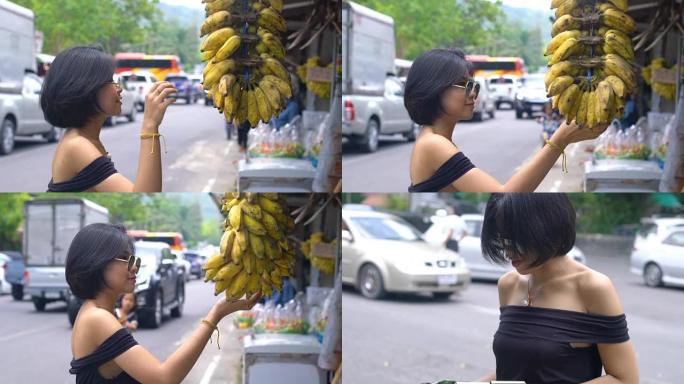 年轻的亚洲妇女在市场上购买香蕉