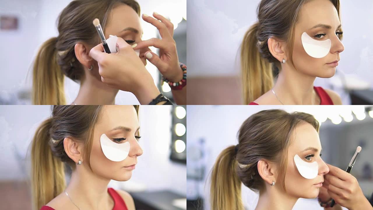 化妆师在涂眼妆的同时使用白色眼贴来保护皮肤和化妆。特写视图