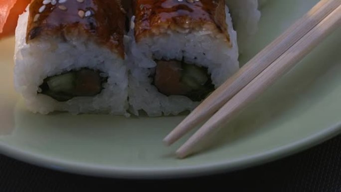 开胃的惊人的 “龙” 方形寿司卷，鳗鱼，鲑鱼，黄瓜，紫菜，寿司饭，芝麻。盘。筷子、腌制生姜和芥末。特