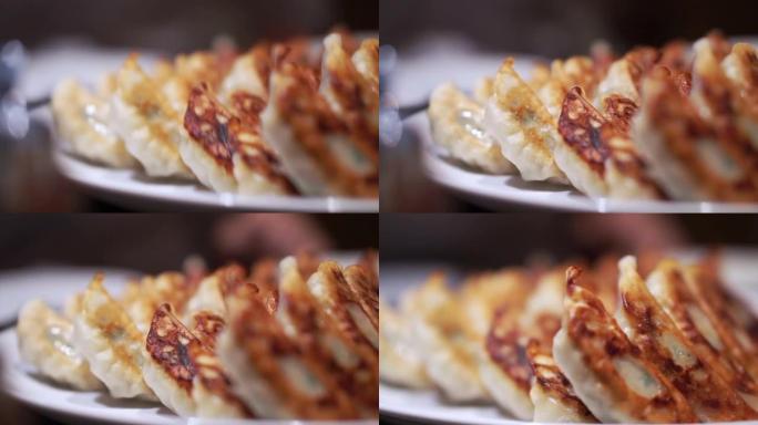 盘子里装满了美味的日本饺子，一侧有焦皮。用筷子吃饭